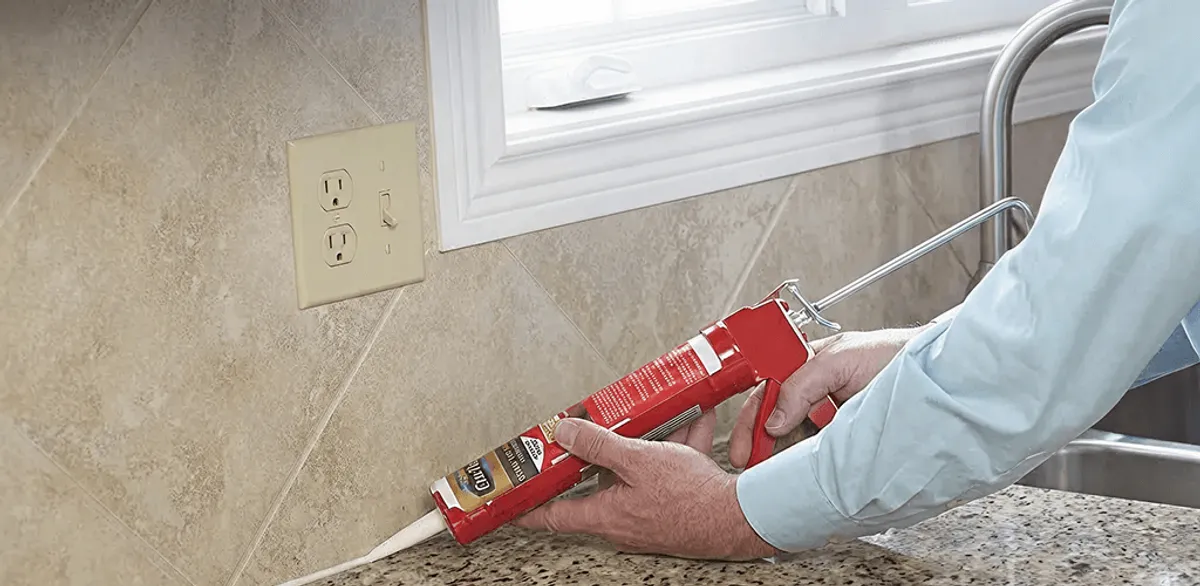 Handyman applying caulk along a kitchen backsplash and countertop seam in Stamford, CT