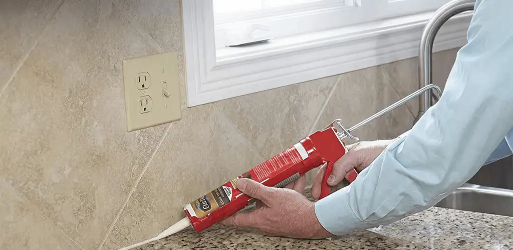 Handyman applying caulk along a kitchen backsplash and countertop seam in Stamford, CT