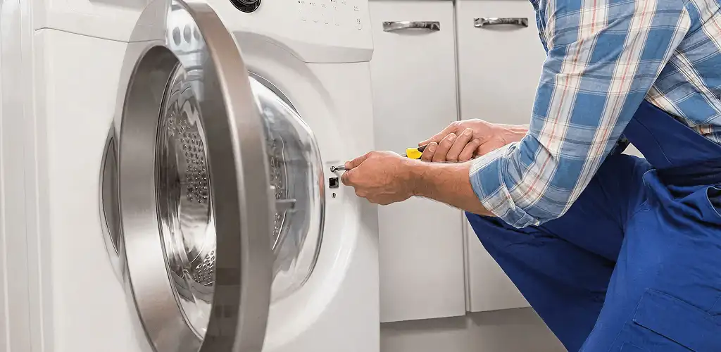 Handyman repairing a clothes dryer and checking electrical connections in Stamford, CT