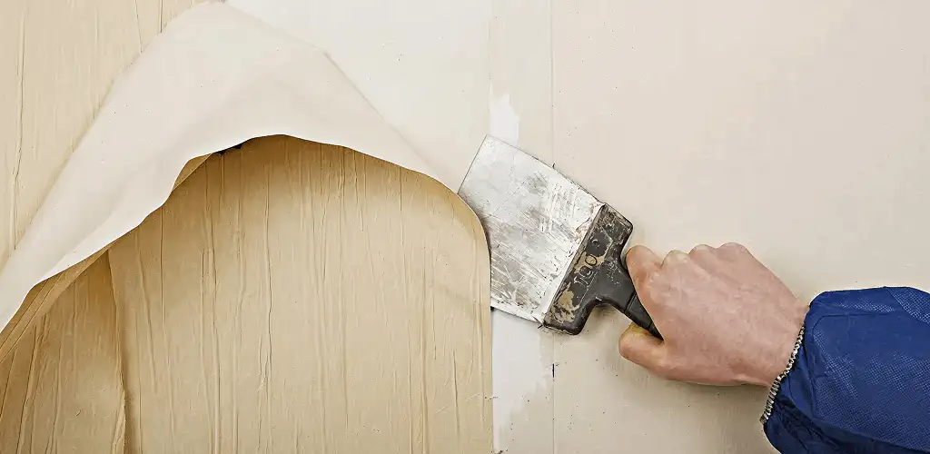 Handyman removing wallpaper with a scraper for wall preparation in Stamford, CT