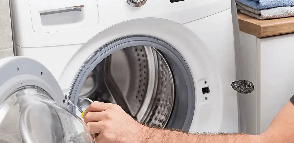 Handyman repairing a front-load washing machine and inspecting the drum in Stamford, CT