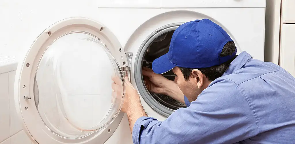 Washing machine repair handyman inspecting a front-load washer drum in Stamford, CT