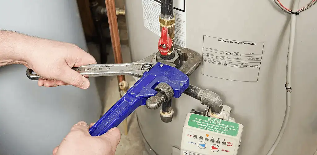 Water heater repair technician tightening the shutoff valve and supply line in Stamford, CT